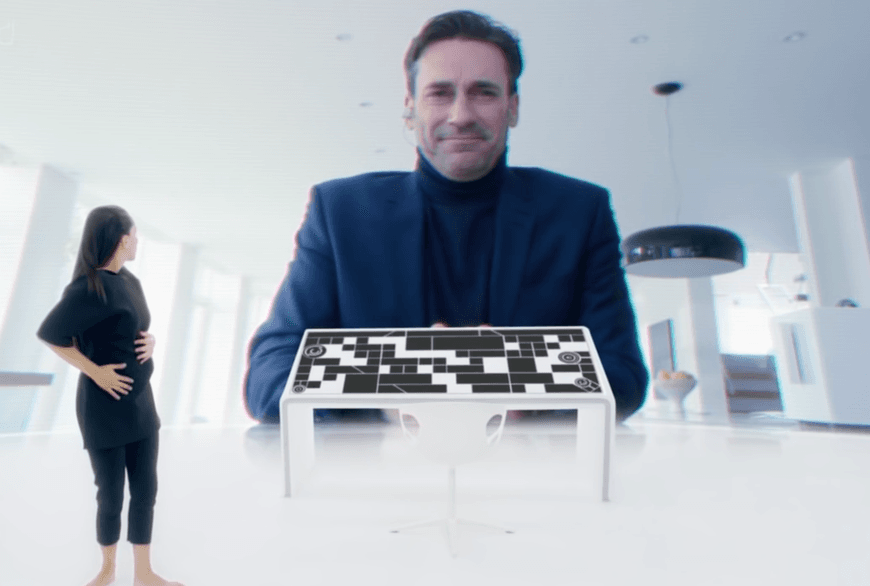 画像には、大きなスクリーンの前に立つ女性と、微笑みながら彼女に寄り添う男性が写っている。女性の前には近未来風の操作卓がある。